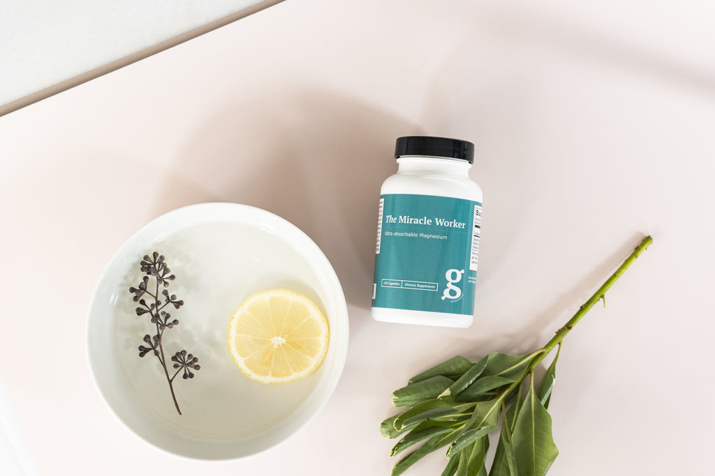 GutPersonal's miracle worker supplement on a table with a bowl of water and lemon.