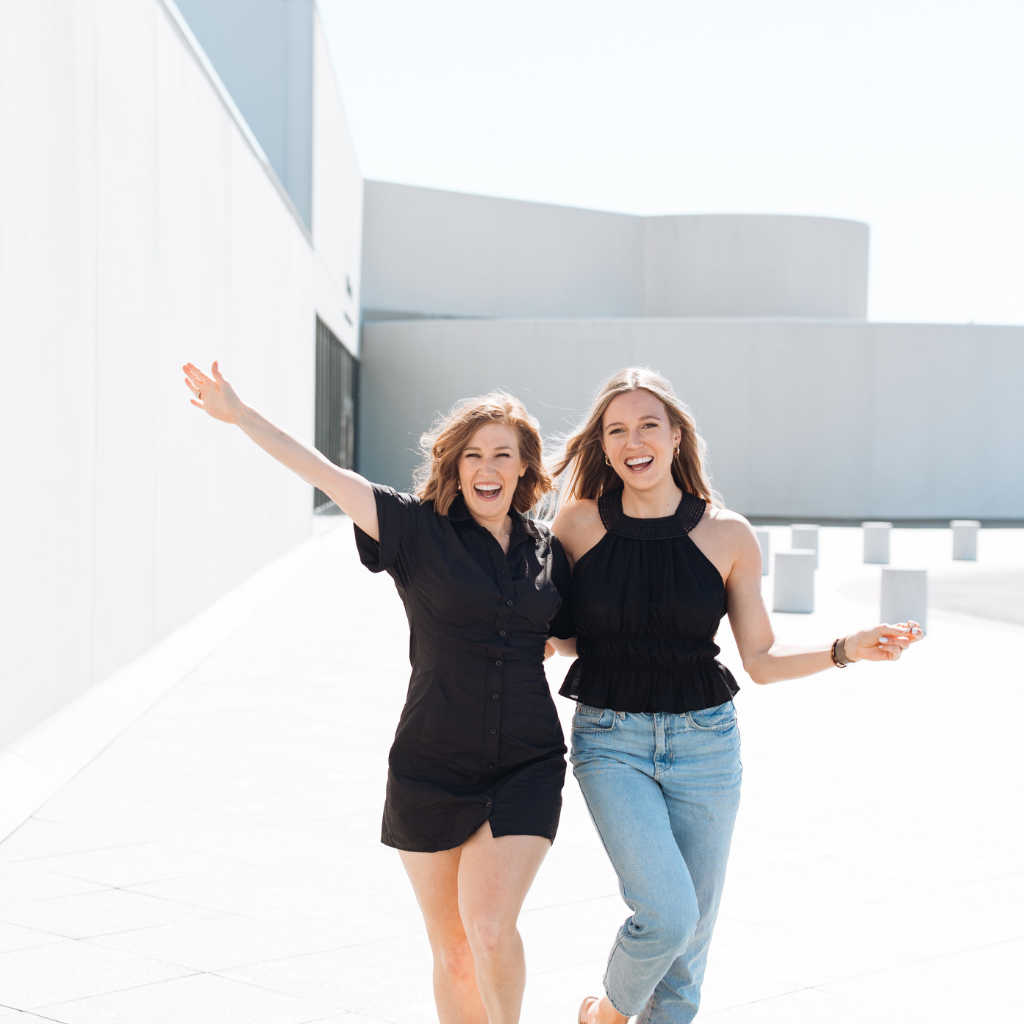 two women walking with their arms in the air