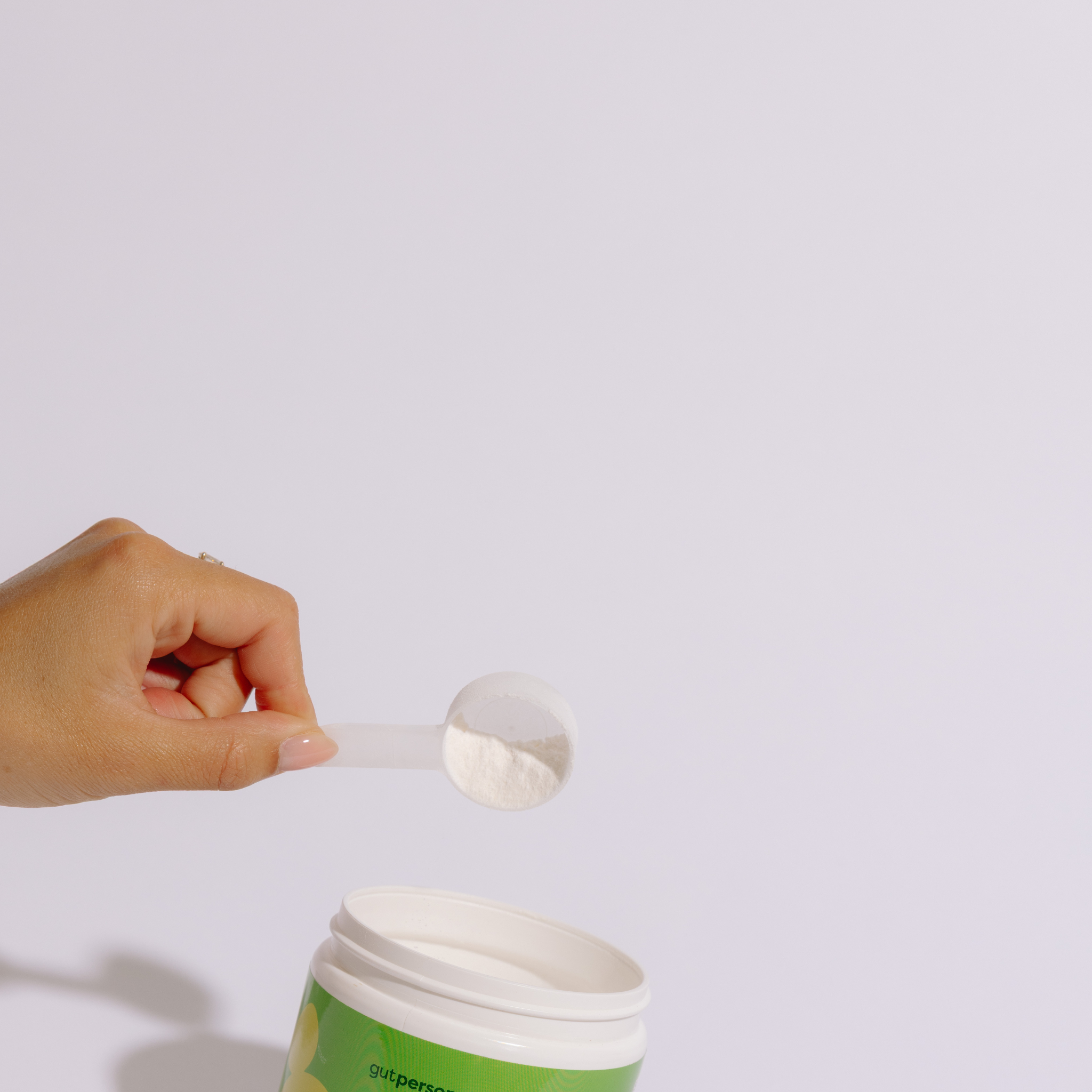 Hand scooping powder from a container with a white background